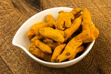 Tumeric kökü yığın içinde kase ahşap arka plan üzerinde