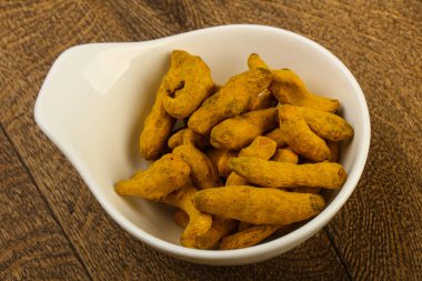 Tumeric kökü yığın içinde kase ahşap arka plan üzerinde