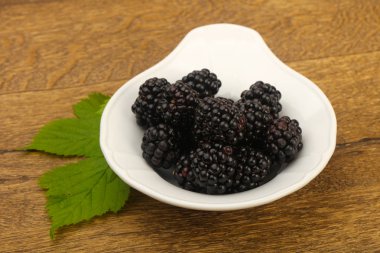 Böğürtlen yaprağı ahşap arka plan üzerinde beyaz plaka