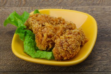 Çıtır tavuk kanatları ile salata yaprakları üzerinde ahşap arka plan