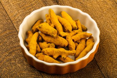 Tumeric kökü yığın içinde kase ahşap arka plan üzerinde