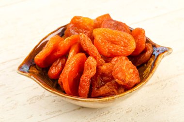 Kuru Kayısı yığın içinde kase ahşap arka plan üzerinde