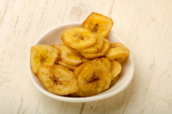 Dry banana chips over wooden background