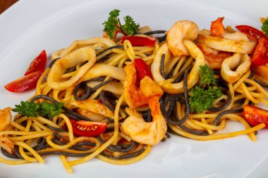 Kızarmış karides, kalamar ve domates ile lezzetli deniz ürünleri makarna