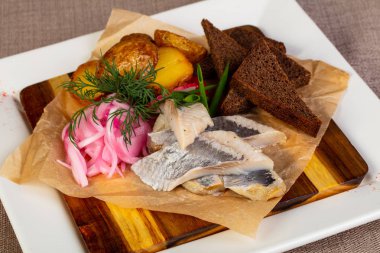 Dilimlenmiş patates ile ringa balığı filetosu