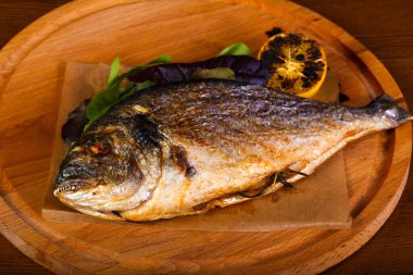 Ahşap arka plan üzerinde limonlu ızgara dorada