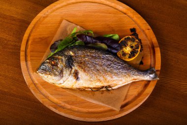 Ahşap arka plan üzerinde limonlu ızgara dorada