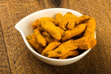 Tumeric kökü yığın içinde kase ahşap arka plan üzerinde