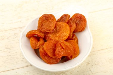 Kuru Kayısı yığın içinde kase ahşap arka plan üzerinde