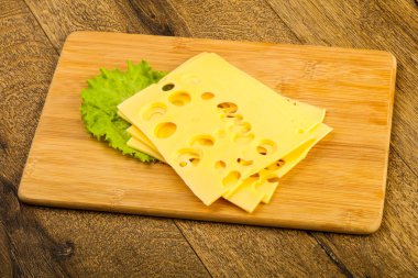 Ahşap arka plan üzerinde dilimlenmiş peynir salata yaprakları