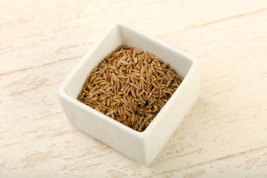Kimyon tohumları yığın içinde kase ahşap arka plan üzerinde