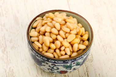 Sedir fındık yığın içinde kase ahşap arka plan üzerinde