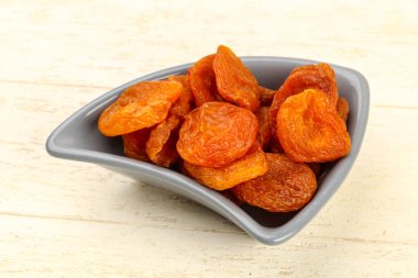 Kuru Kayısı yığın içinde kase ahşap arka plan üzerinde