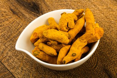 Tumeric kökü yığın içinde kase ahşap arka plan üzerinde