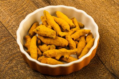 Tumeric kökü yığın içinde kase ahşap arka plan üzerinde