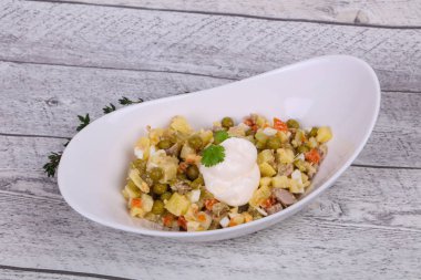 Geleneksel Rus salatası, ahşap arka planda beyaz kasede tavuk var.