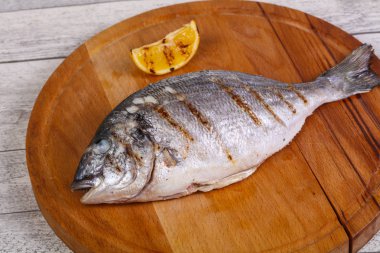 Tahtanın üzerinde limonlu ızgara dorada.