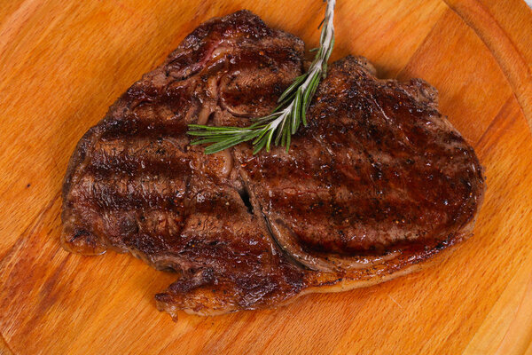 Ribeye steak with rosemary over the wooden board