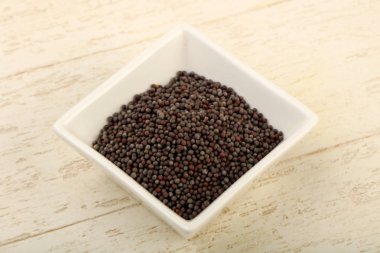 Kase ahşap arka plan üzerinde siyah hardal tohumu yığın