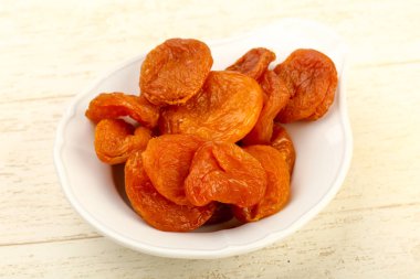 Kuru Kayısı yığın içinde kase ahşap arka plan üzerinde