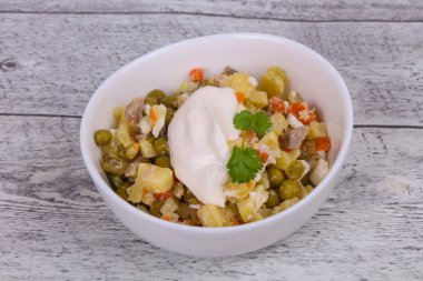 Geleneksel Rus salatası, ahşap arka planda beyaz kasede tavuk var.