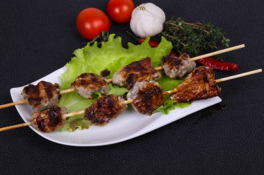 Salata yapraklı ve domatesli domuz kebabı kekik ve garkik servis edilir.