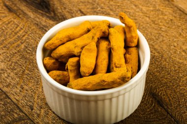 Tumeric kökü yığın içinde kase ahşap arka plan üzerinde