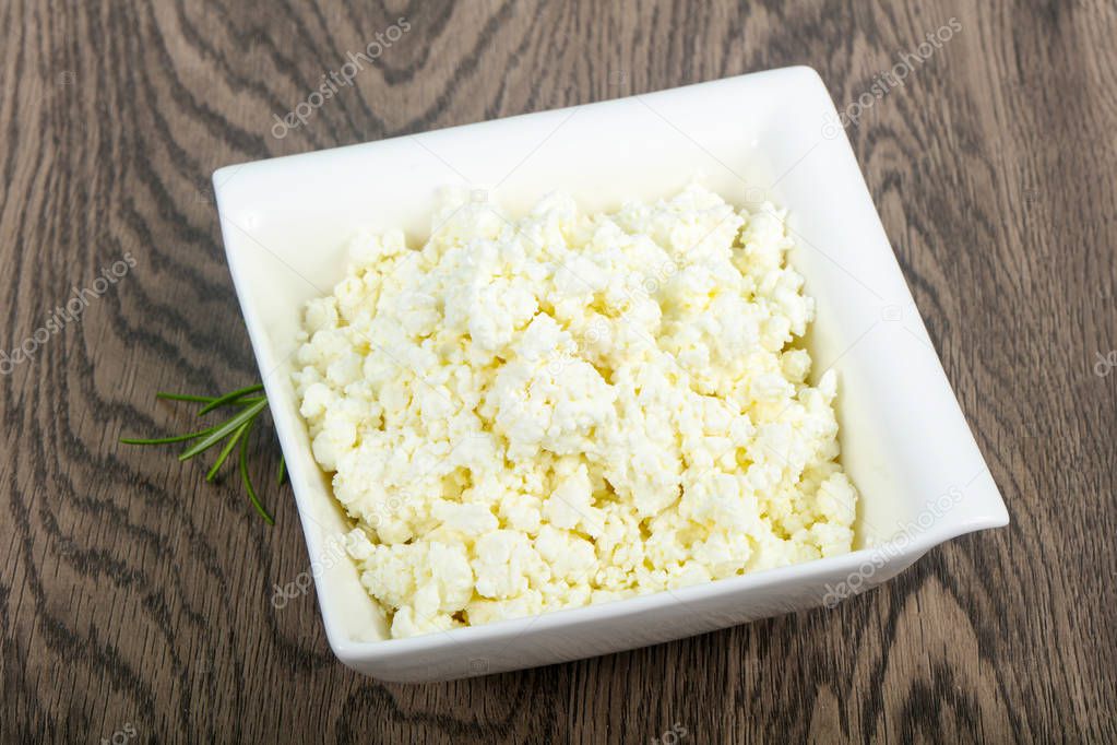 Cottage cheese in the bowl over wooden