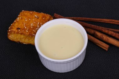 Condenced milk in the bowl with sinnamon sticks and pastry clipart