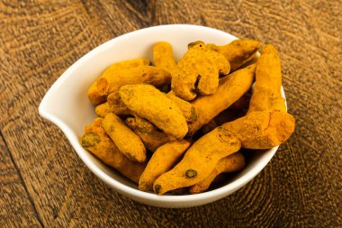 Tumeric kökü yığın içinde kase ahşap arka plan üzerinde