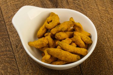 Tumeric kökü yığın içinde kase ahşap arka plan üzerinde