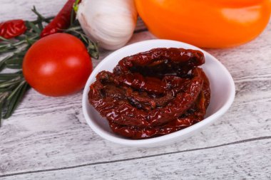 Kavanozda kurutulmuş domates, zeytinyağı biberiye, salata yaprakları ve sarımsak.