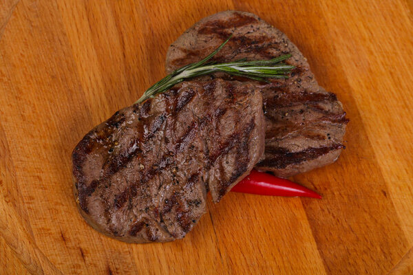Grilled Fillet Mignon with rosemary and chili pepper over the wooden background