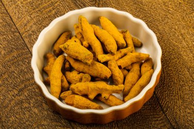 Tumeric kökü yığın içinde kase ahşap arka plan üzerinde