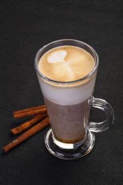 Bardaktaki kapuçino tarçın çubukları servis ediyordu.