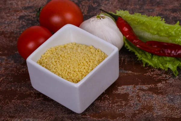 Couscous crudo nella ciotola servito insalata foglie, pomodoro e pepe — Foto Stock