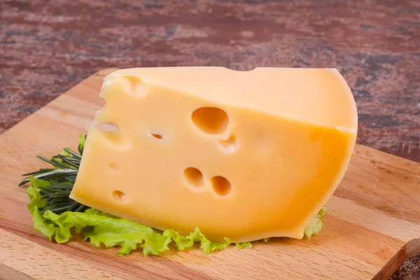 Queso Maasdam en la tabla sirve hojas de ensalada —  Fotos de Stock