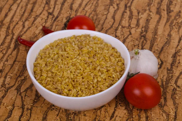 Raw bulgur in the bowl with tomatoes and garlic — Stock Photo, Image