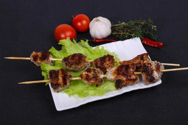 Brochettes de kebab de porc dans l'assiette avec feuilles de salade et tomates — Photo