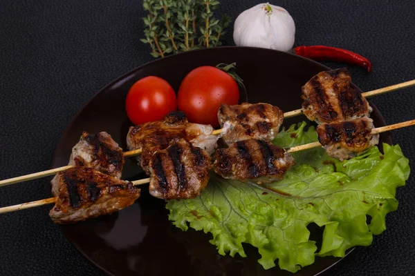 Brochettes de kebab de porc dans l'assiette avec feuilles de salade et tomates — Photo