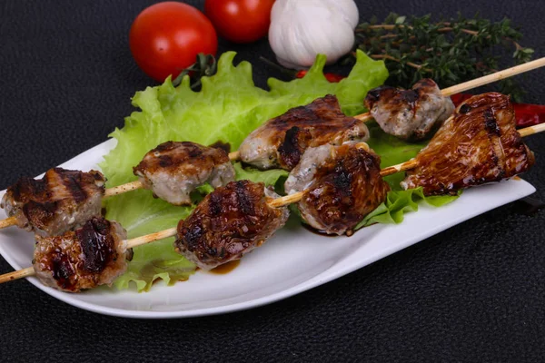 Spieße aus Schweinefleisch auf dem Teller mit Salatblättern und Tomaten — Stockfoto