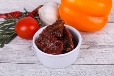 Kavanozda kurutulmuş domates, zeytinyağı biberiye, salata yaprakları ve sarımsak.