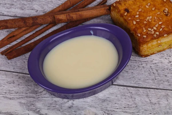 Condenced milk in the bowl with sinnamon and pastry — Stock Photo, Image