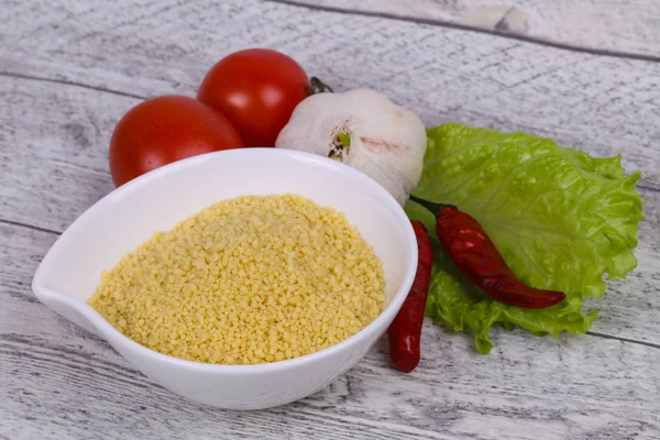 Couscous cru dans le bol servi feuilles de salade, tomate et poivre — Photo