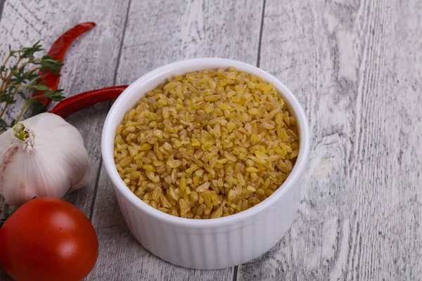 Roher Bulgur in der Schüssel mit Tomaten und Knoblauch — Stockfoto