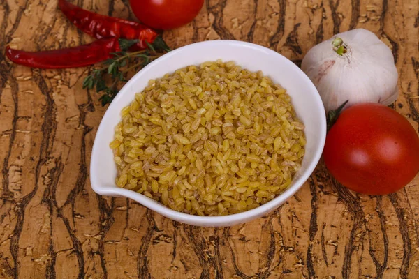 Raw bulgur in the bowl with tomatoes and garlic — Stock Photo, Image