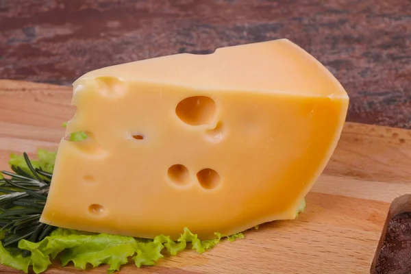 Maasdam ost i styrelsen serveras salladsblad — Stockfoto