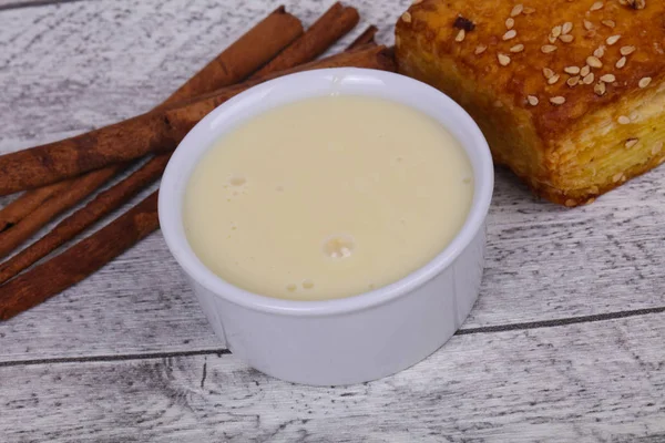 Condenced milk in the bowl with sinnamon and pastry — Stock Photo, Image