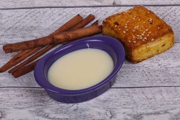 Condenced milk in the bowl with sinnamon and pastry — Stock Photo, Image