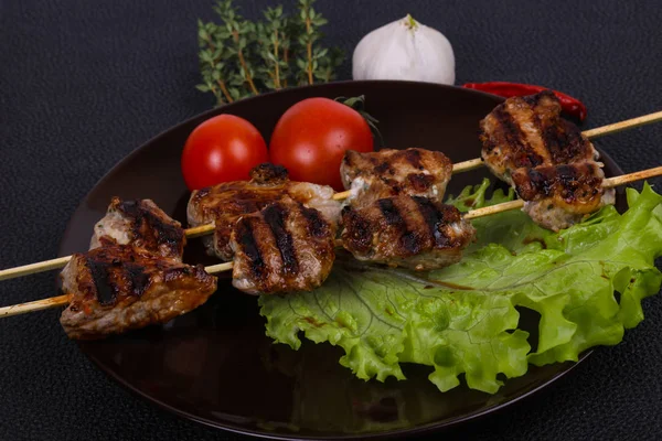 Brochettes de kebab de porc dans l'assiette avec feuilles de salade et tomates — Photo